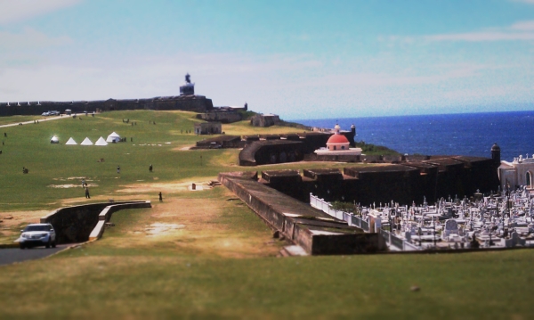 A cemetery sits between Castillo de San Cristobal and the monument of El Morro in the distance.